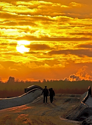 Um casal caminhando em direção ao pôr do sol