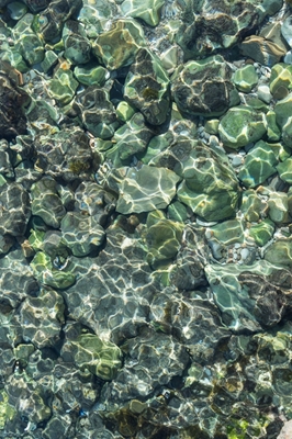 Blågrønt sjøvann i en steinete bukt
