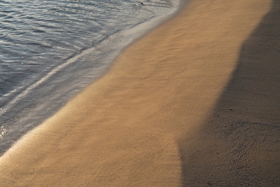 Sand og havvand ved solopgang