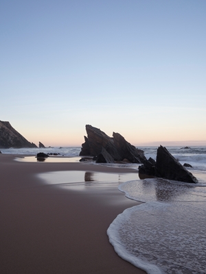 Stenar på stranden vid soluppgången.