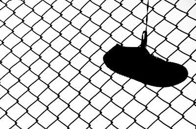 Shoe silhouette against fence