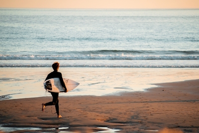 Laufen zum Surfen bei Sonnenuntergang